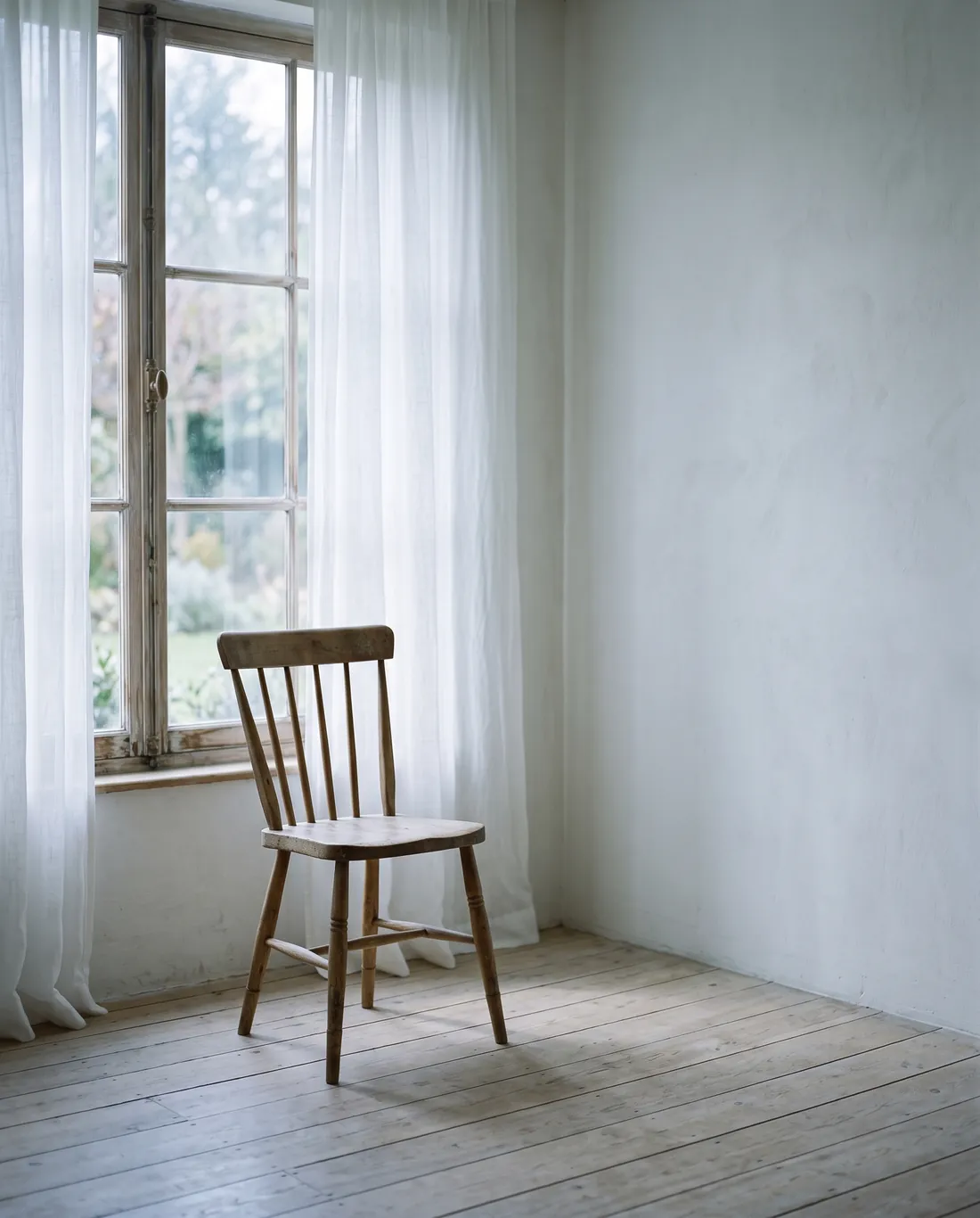Una silla vacía junto a una ventana, en una habitación tranquila